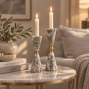 A pair of elegant tapered candlesticks with gray and white marbled stone-like bodies and polished gold-tone neck accents, displayed on a light gray studio background.