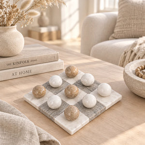 A marble checkers game board with alternating white and gray checkered squares, featuring nine polished marble balls in off-white and light brown arranged on the board, set against a plain white background.