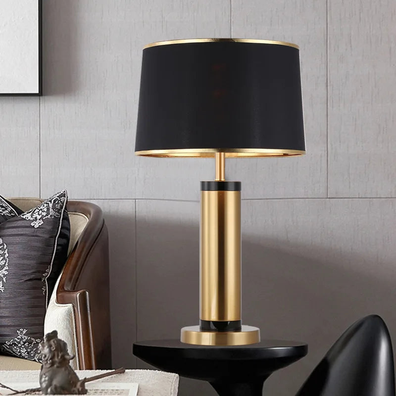 Modern table lamp with black shade and gold base on a side table.
