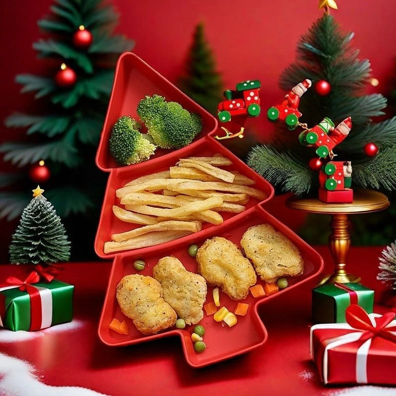 A red Christmas tree-shaped serving tray filled with broccoli, fries, and chicken nuggets, styled on a red table with miniature Christmas trees, ornaments, gift boxes, and a small train decoration.