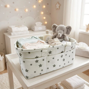 An off-white fabric baby storage basket with a pattern of dark gray stars, featuring multiple compartments and two fabric handles.